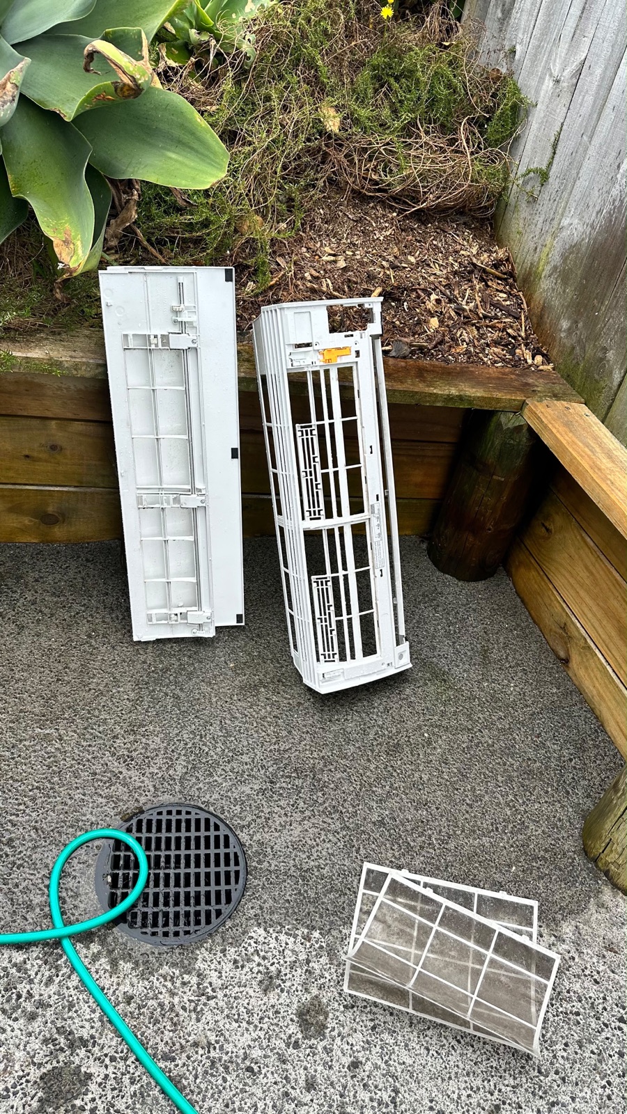 Heat pump covers and filters removed and washed clean, drying outside next to the hose