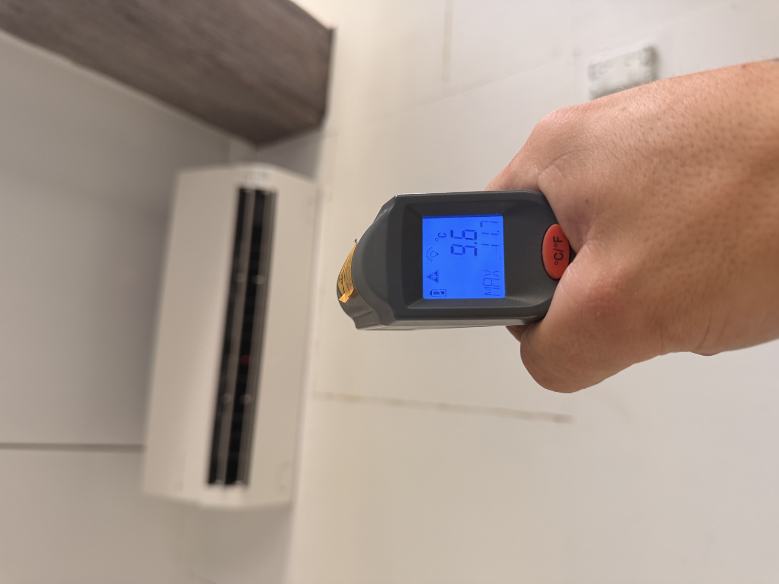 MV Climate technician checking the outlet air temperature of a newly installed high-wall heat pump
