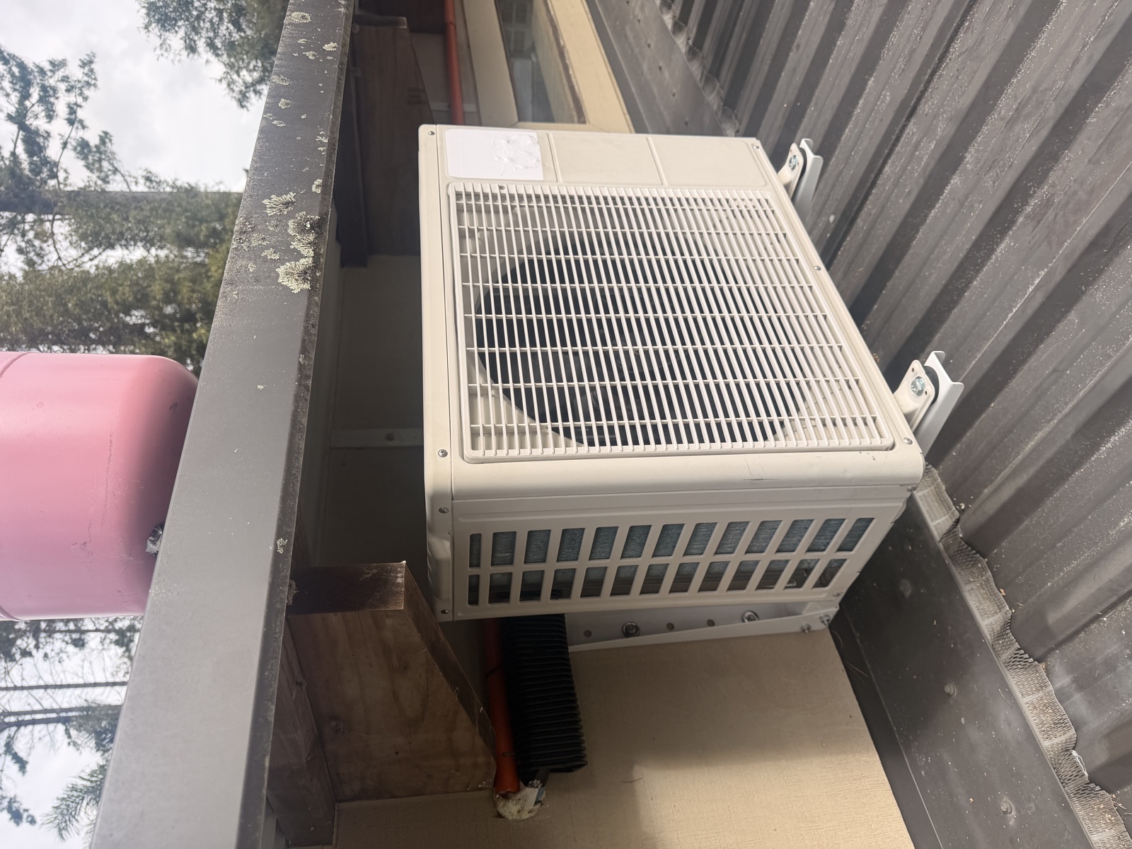 Outdoor heat pump unit bracket mounted on a roof with the line set run into the wall
